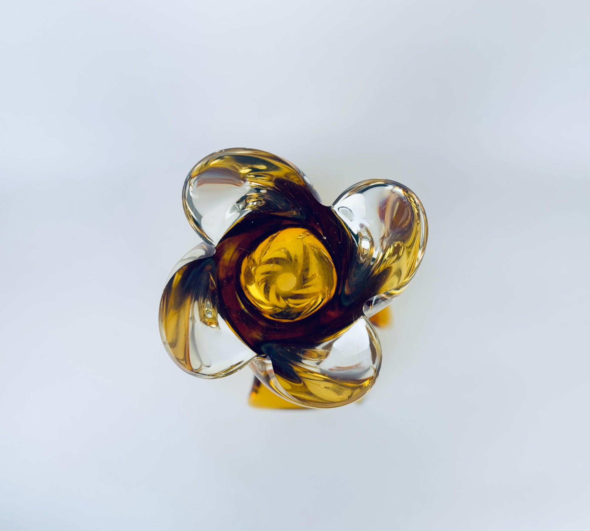 Decorative glass piece with yellow center and clear outer layers on a light gray background