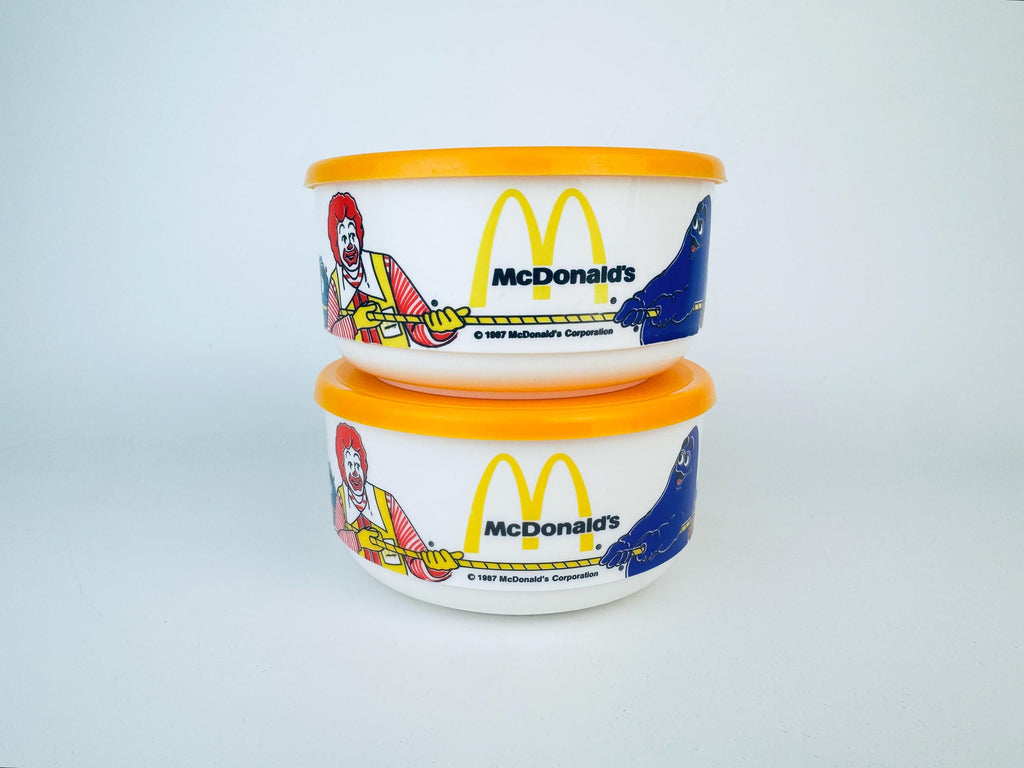 Two McDonald's-themed containers with colorful designs on a light gray background