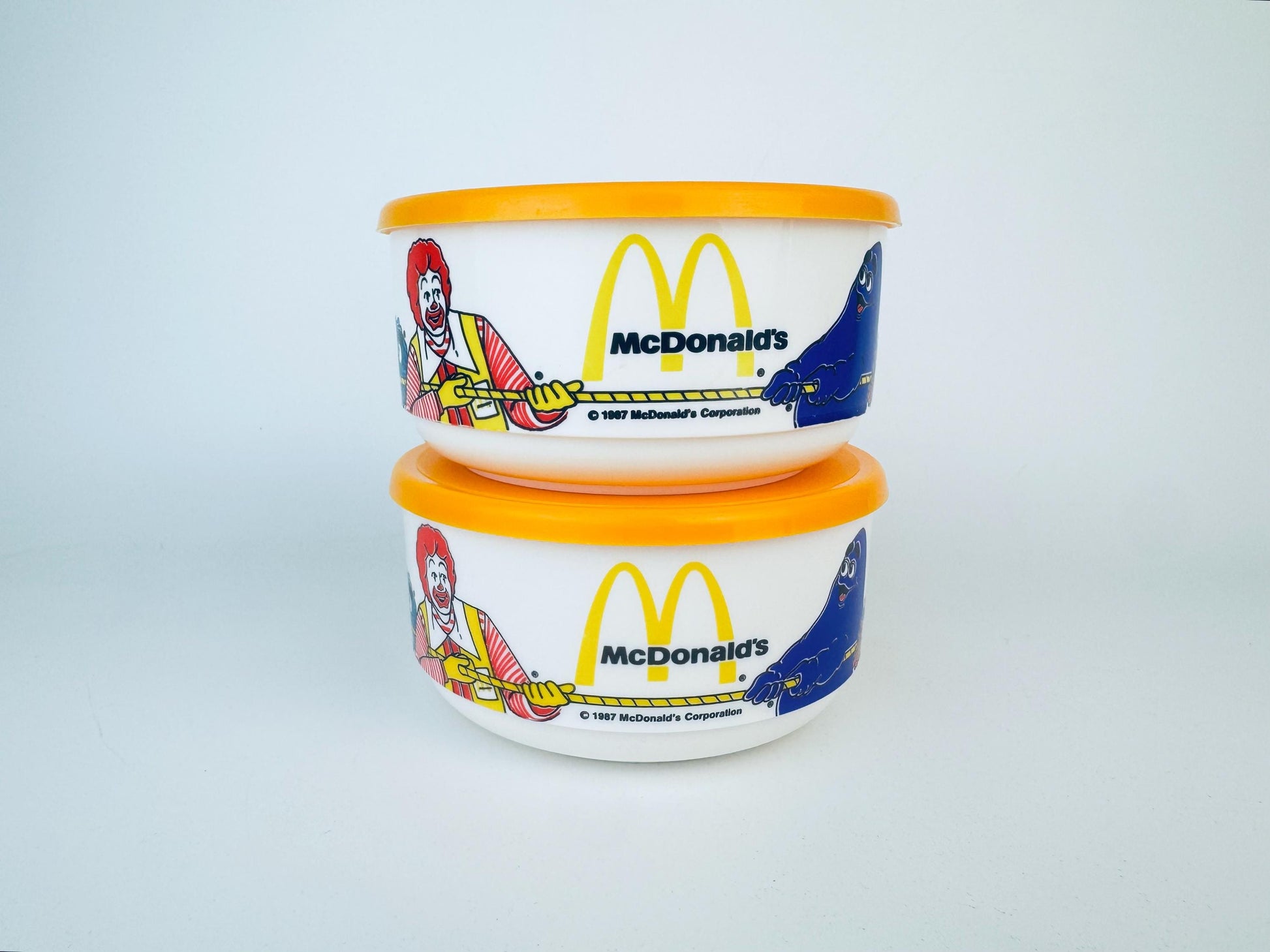 Two McDonald's-themed containers with colorful designs on a light gray background