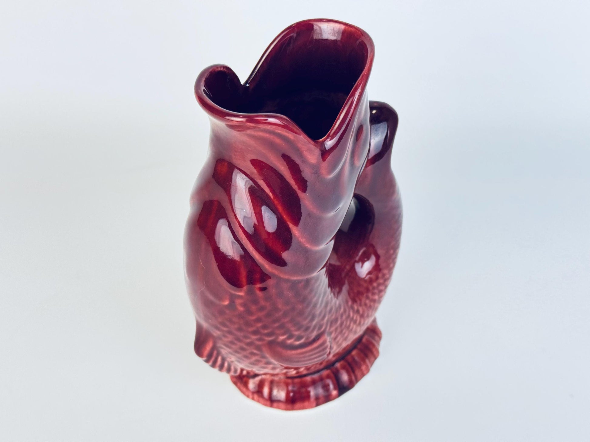 Angled view of pitcher showing interior opening and curved handle-like tail design