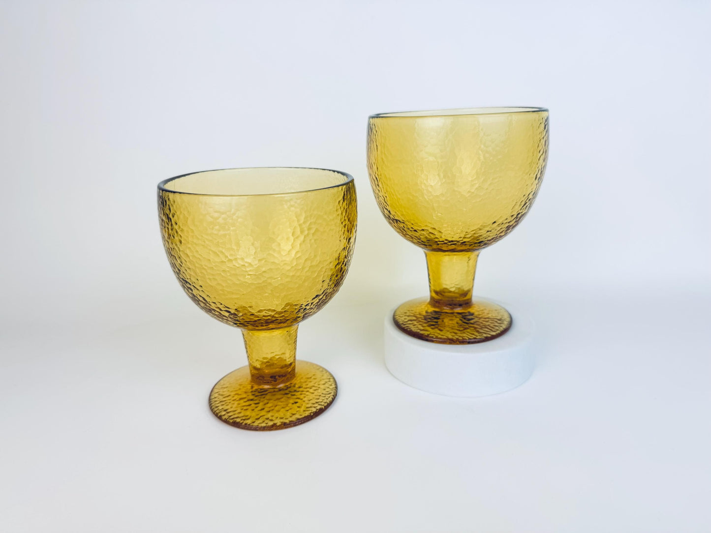 Pair of vintage amber glass goblets with textured surface, shown side by side on white background