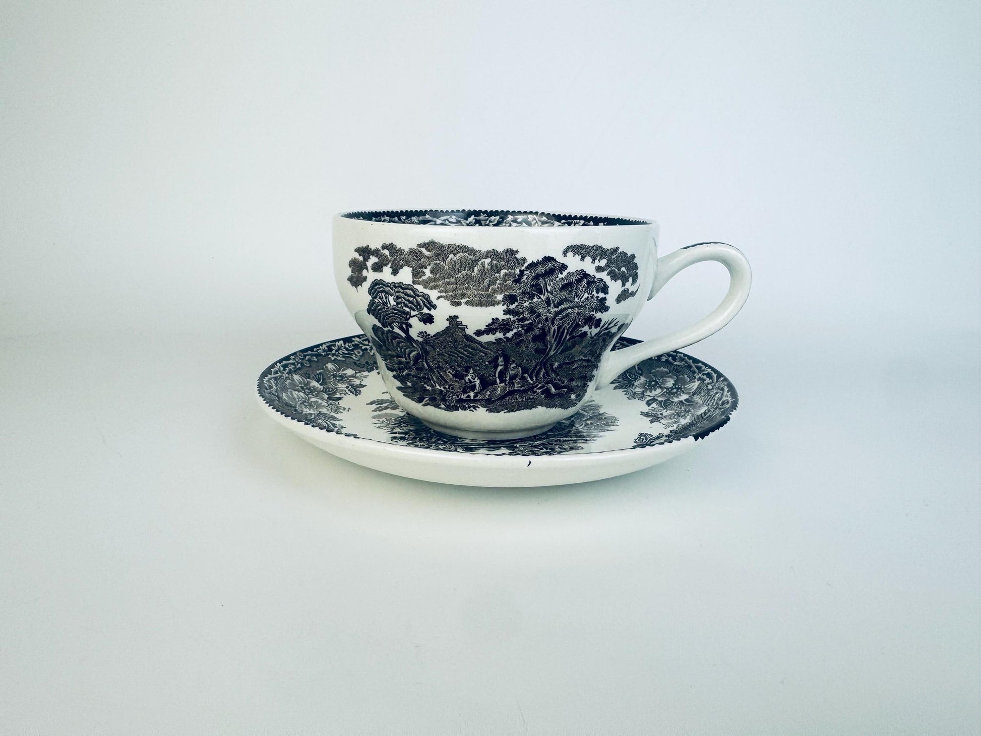 Ceramic cup and saucer with blue floral pattern on a white background