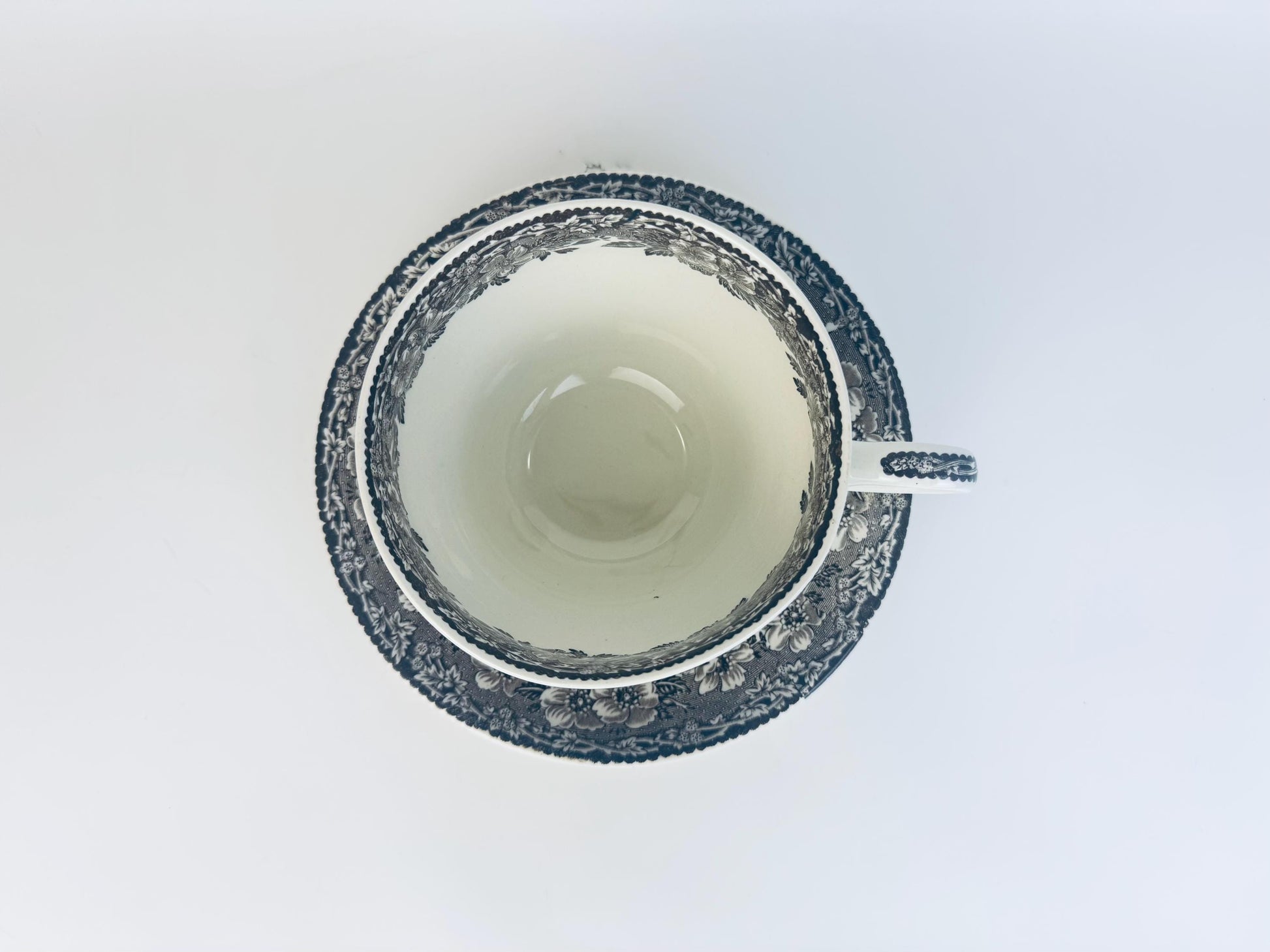 Close-up of a white ceramic cup with a dark gray interior on a light gray background