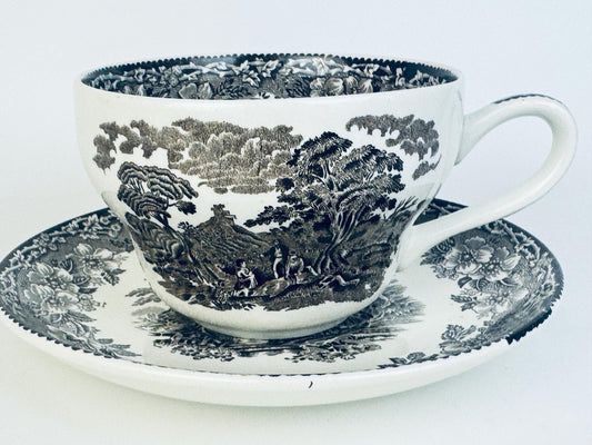Teacup and saucer with black floral pattern on a white background