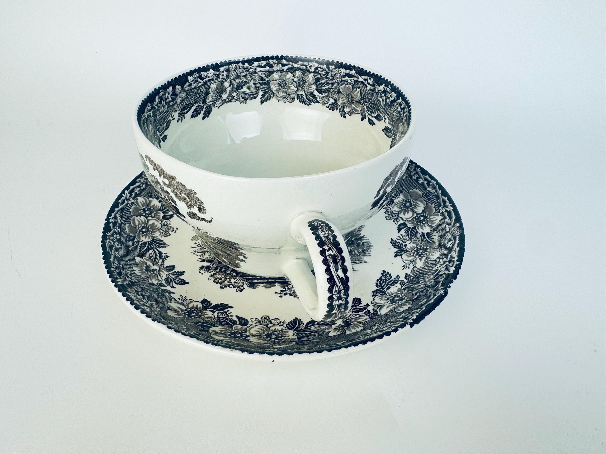 White teacup with blue floral pattern on a matching saucer against a white background