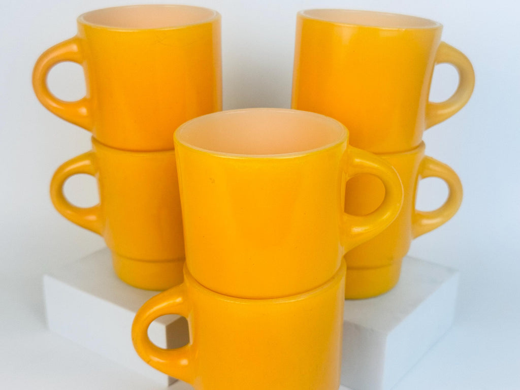 Set of yellow mugs stacked on a white surface