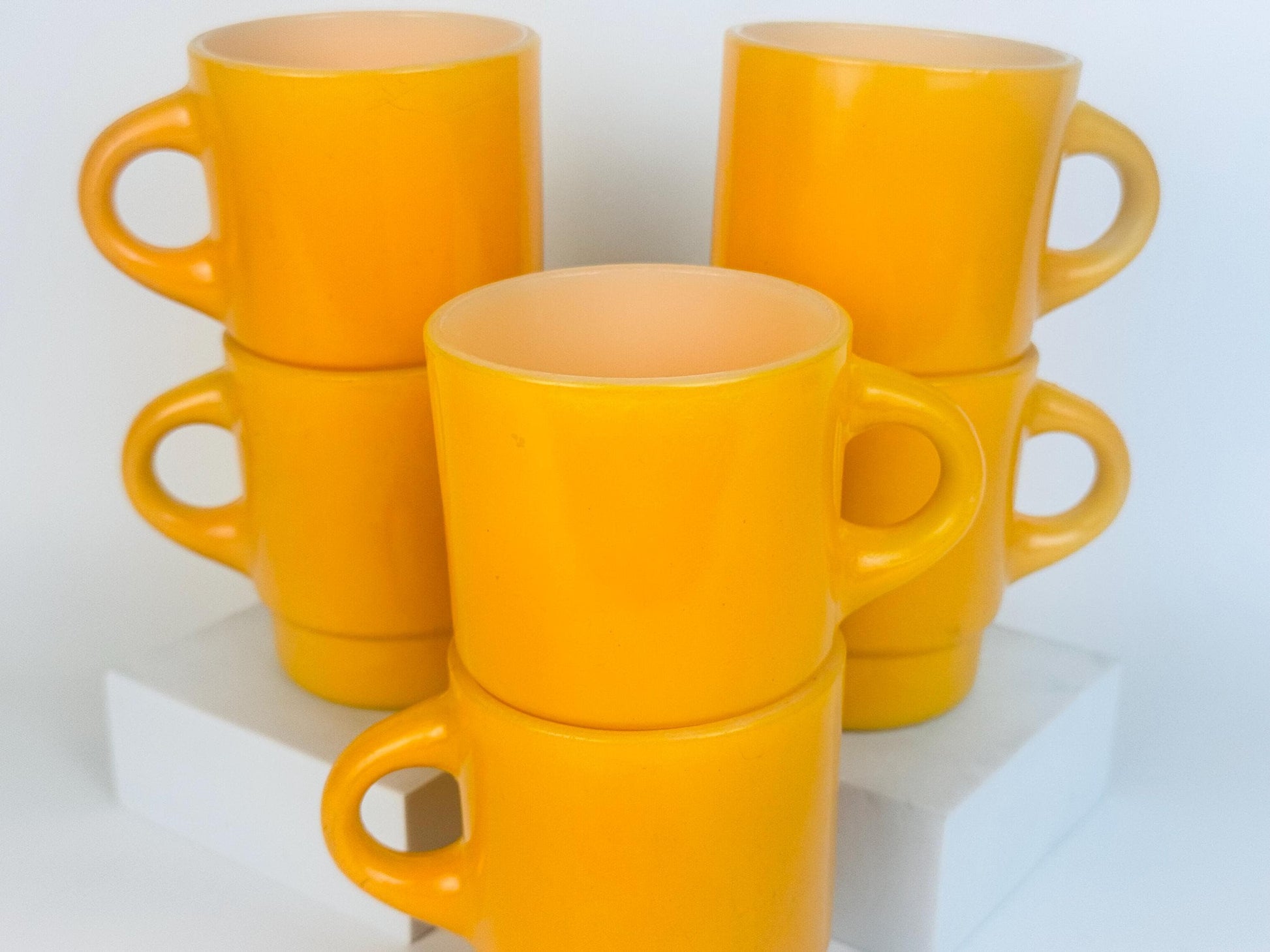 Set of yellow mugs stacked on a white surface