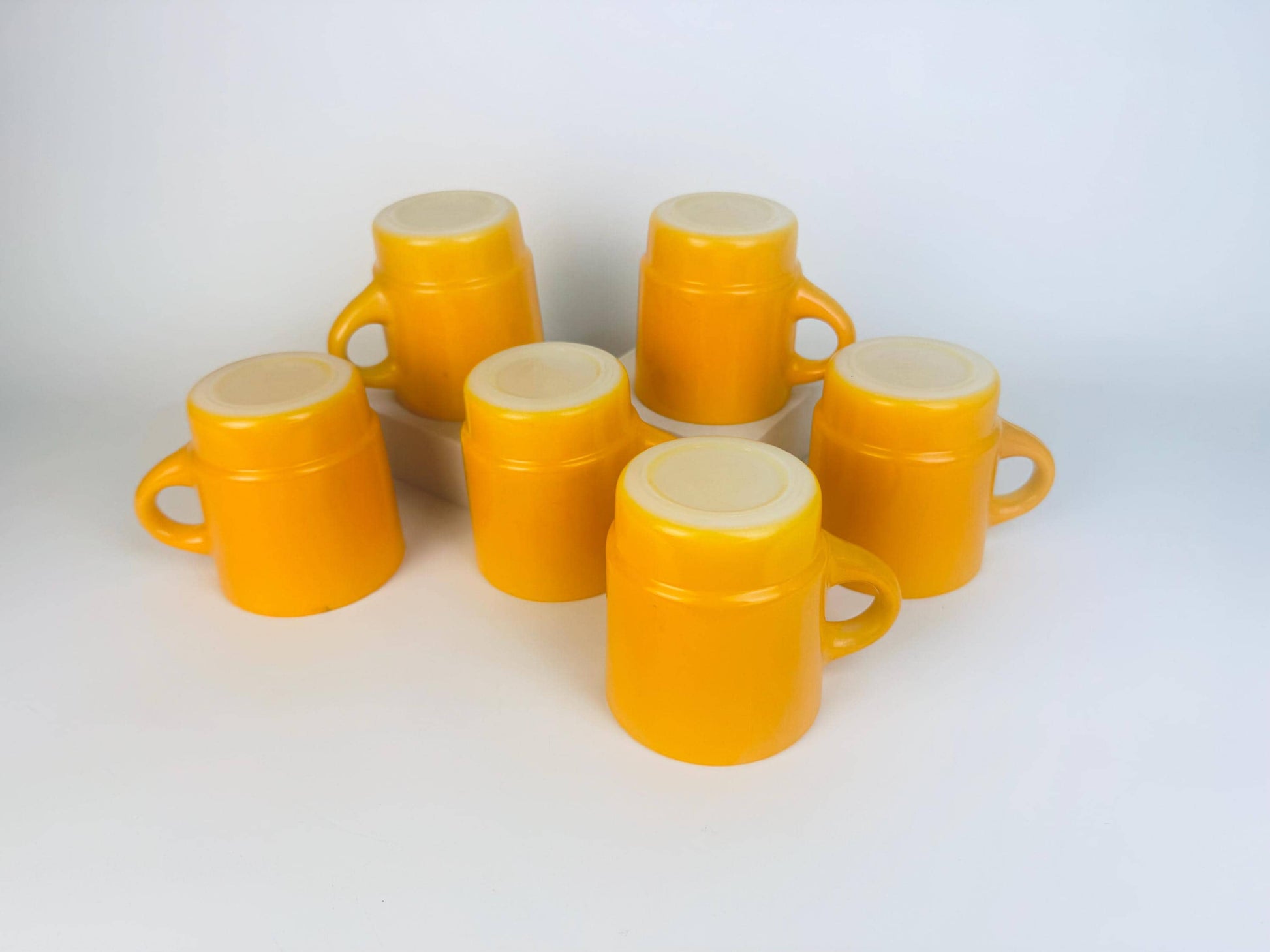 Set of six yellow ceramic mugs on a white background