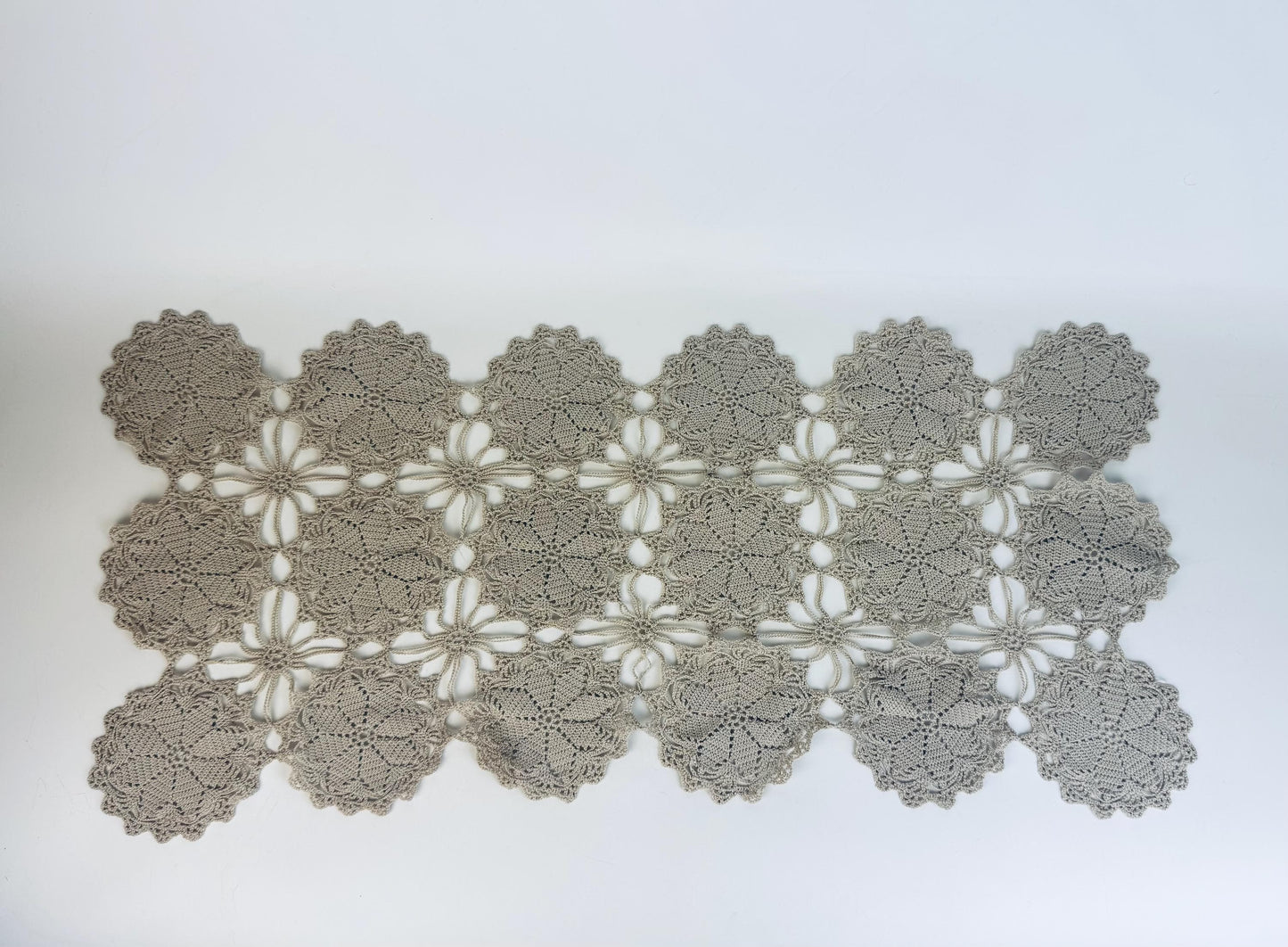 Overhead view of full beige crochet table runner with medallion lace pattern