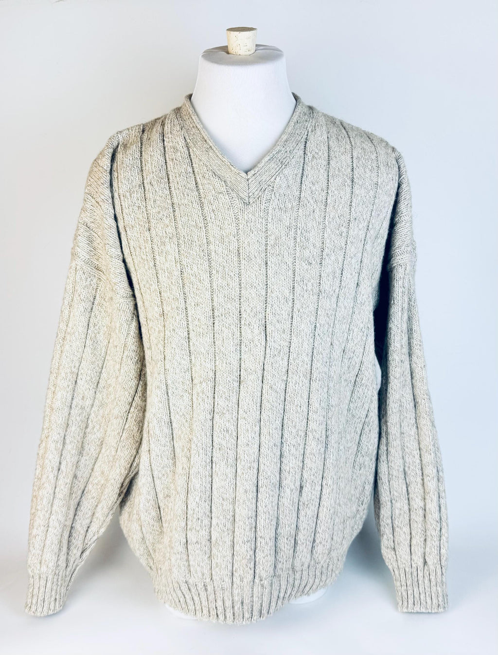 Beige ribbed sweater on a mannequin against a white background