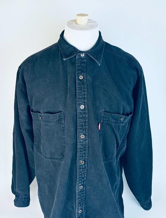 Vintage Levi’s long sleeve denim work shirt in dark blue, displayed on a mannequin against a white background.