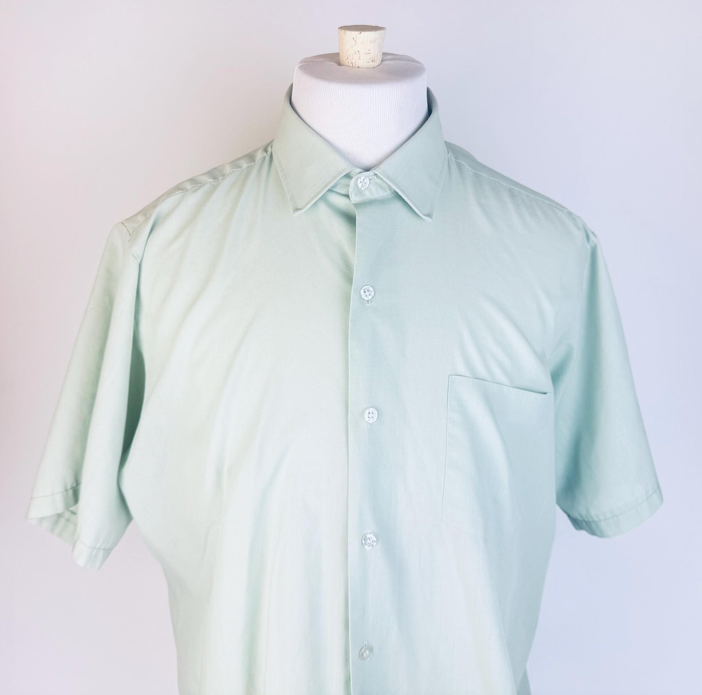 Light green shirt on a mannequin against a plain background