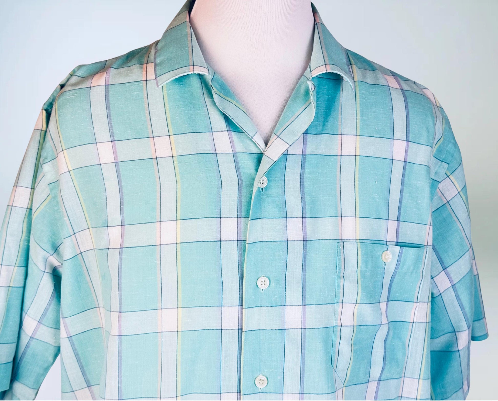 Plaid shirt with light blue, green, and white pattern on a mannequin against a plain background
