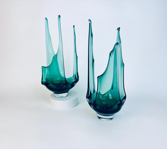 Pair of sculptural emerald green hand-blown glass centrepieces by Jan Benda on a white background.