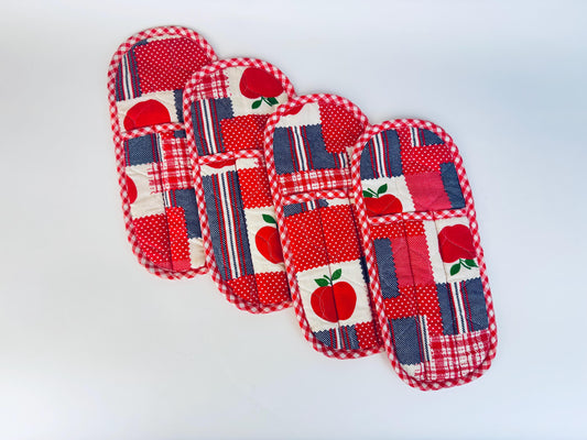 Set of four quilted utensil holders with apple design on a white background