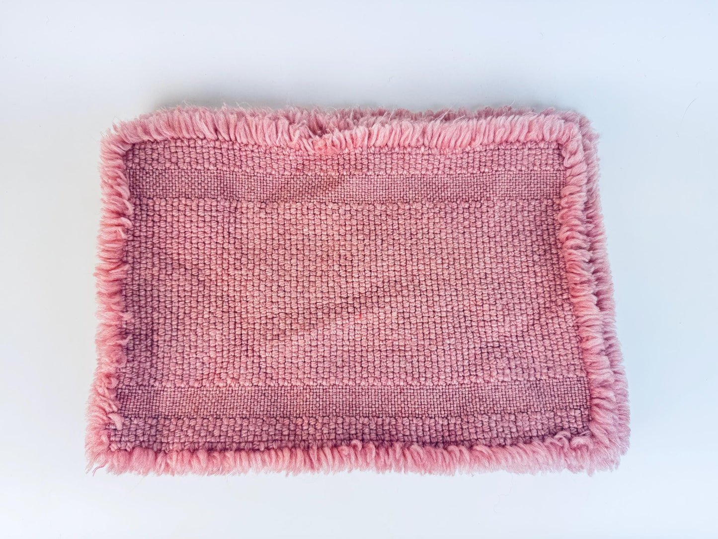 Pink acrylic woven placemats with frayed edges on a white background
