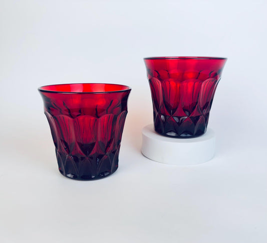 Two red glass tumblers on a white background