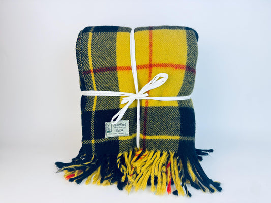 Plaid blanket with yellow and black pattern tied with a white ribbon on a white background