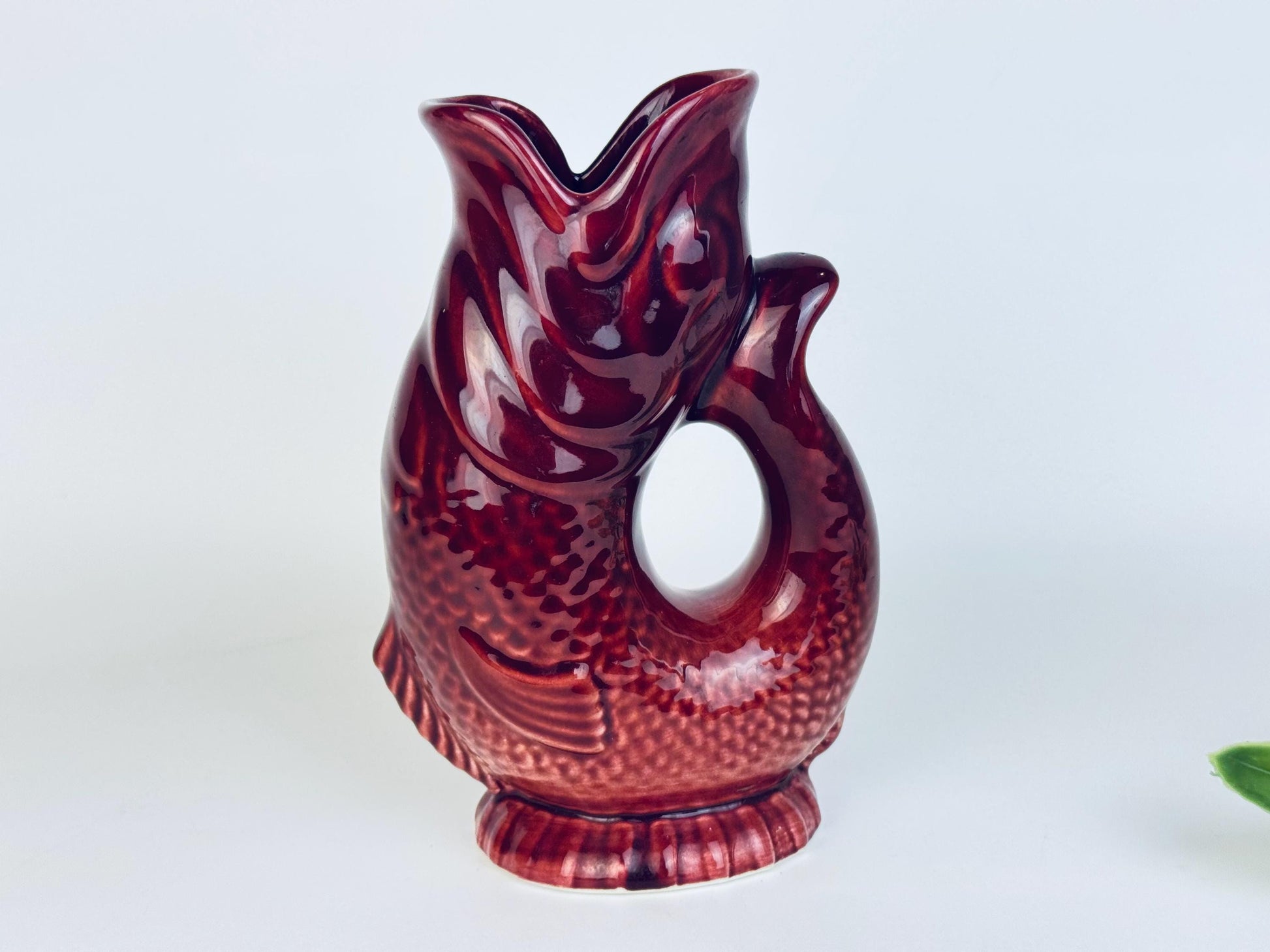 Front view of red ceramic fish jug highlighting detailed scales and textured surface