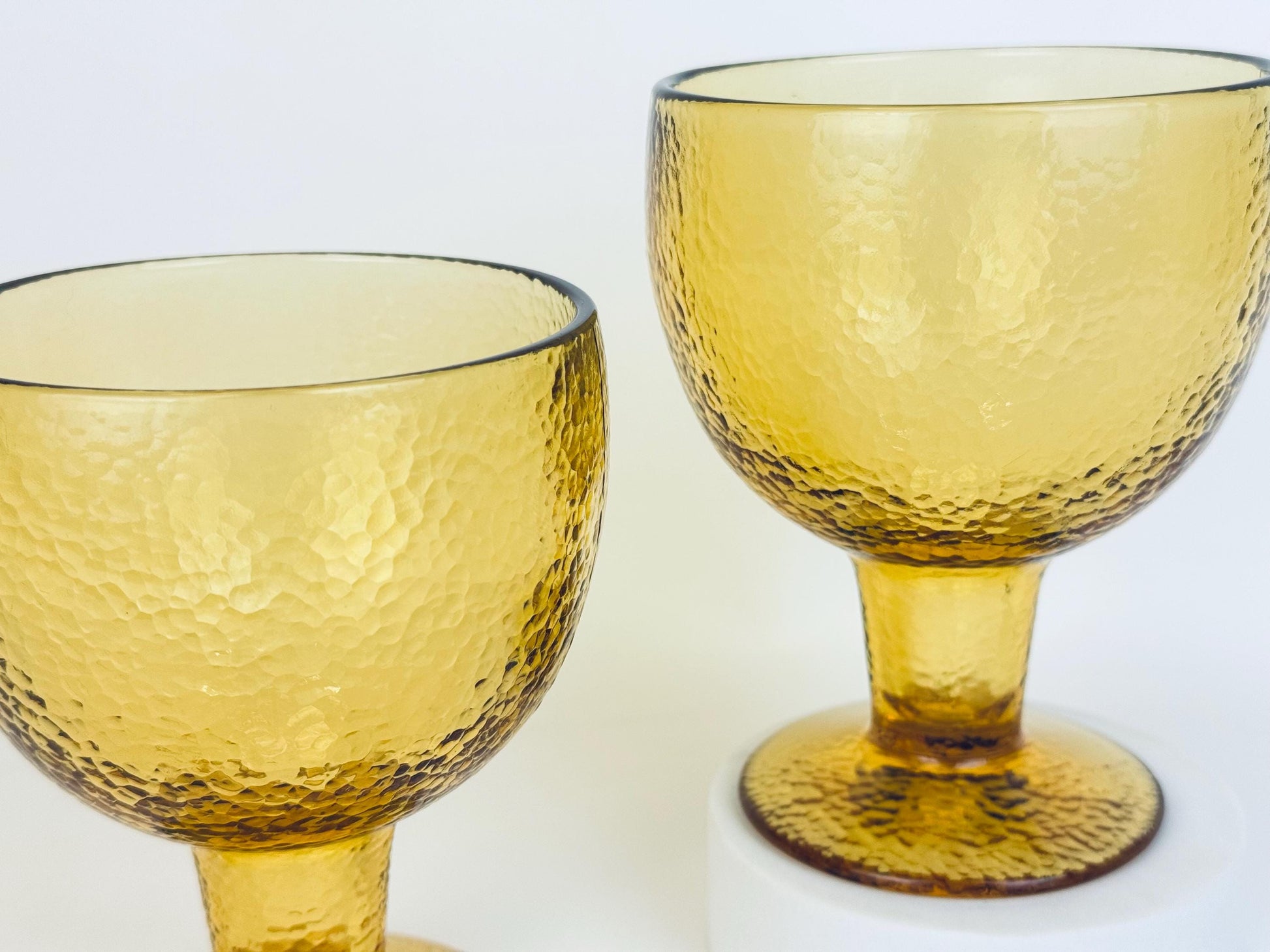 Two amber goblets angled to highlight height and bowl shape, hammered glass texture visible