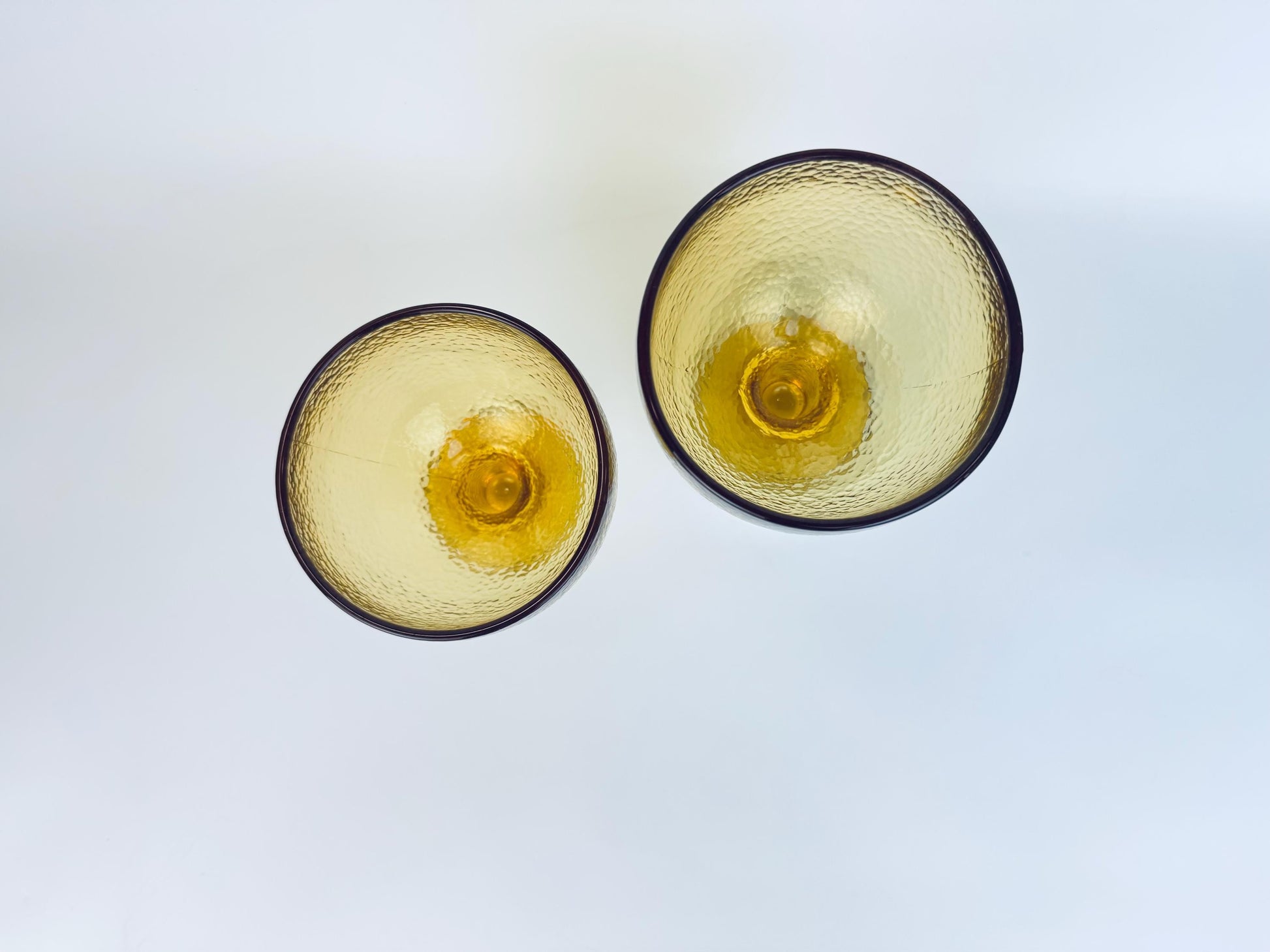 Overhead view of pair of amber goblets showing round rims and golden hue