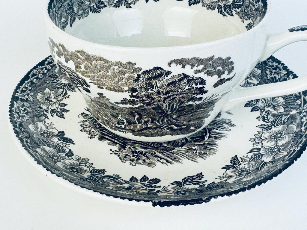 Ceramic teacup and saucer with brown floral pattern on a white background