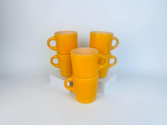 Set of yellow mugs stacked on a white background