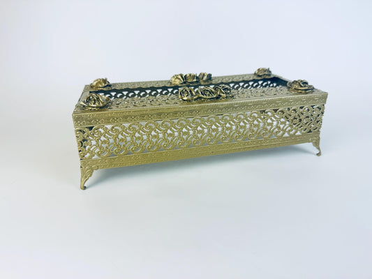 Vintage ornate gold-tone metal facial tissue box cover with filigree sides, raised rose details on the lid, and decorative feet, displayed against a plain white background