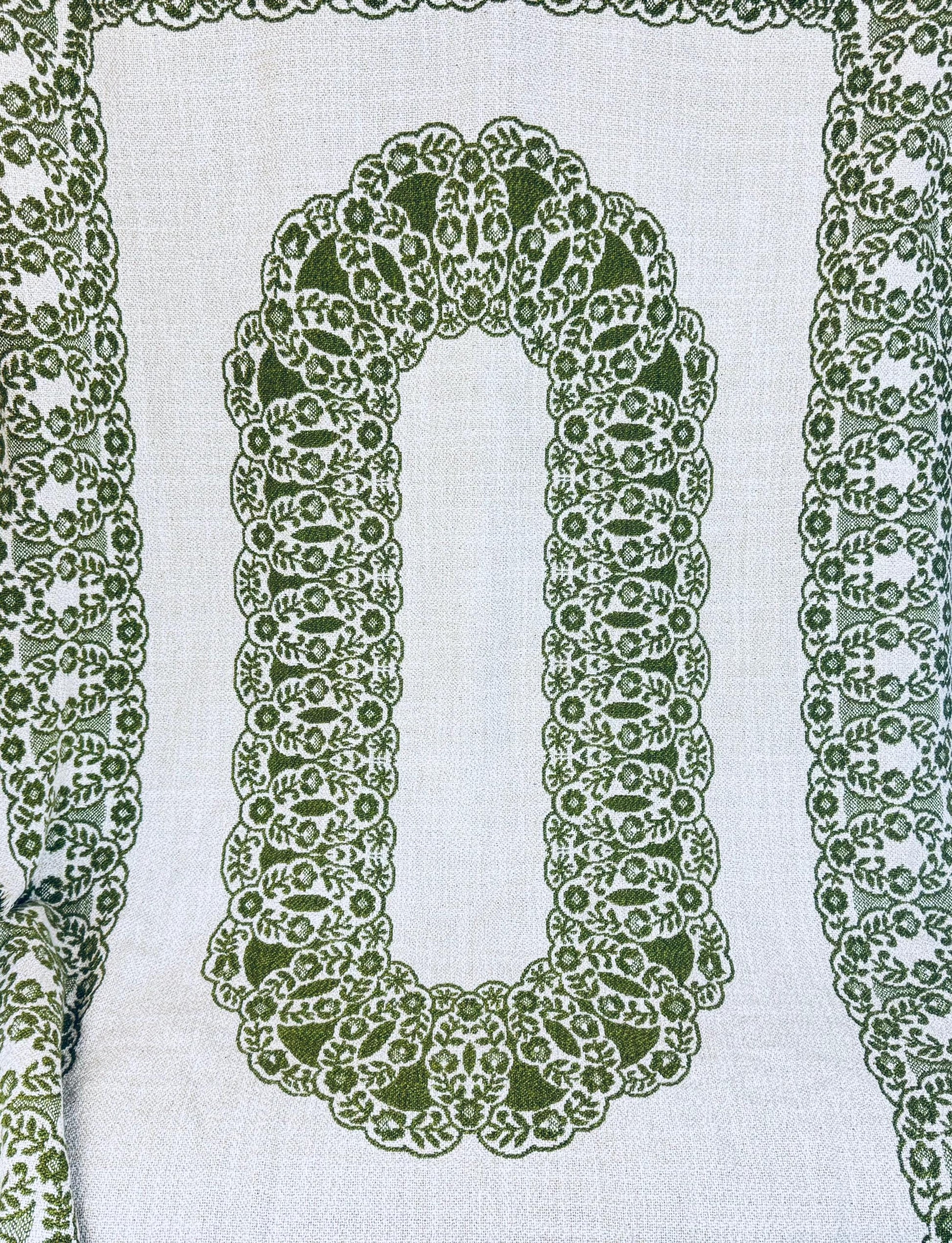 Full view of green and cream jacquard tablecloth with oval floral medallion center