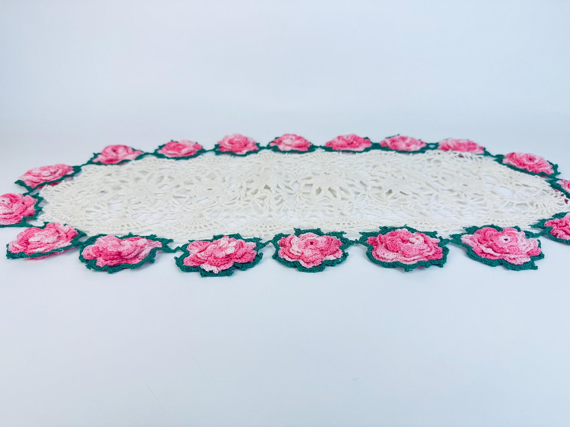 Side angle of full crochet doily showing floral edge and oval shape