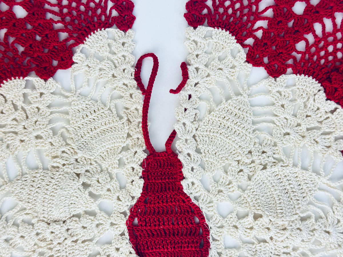 Close-up of crimson butterfly doily showing antennae and fine lace details