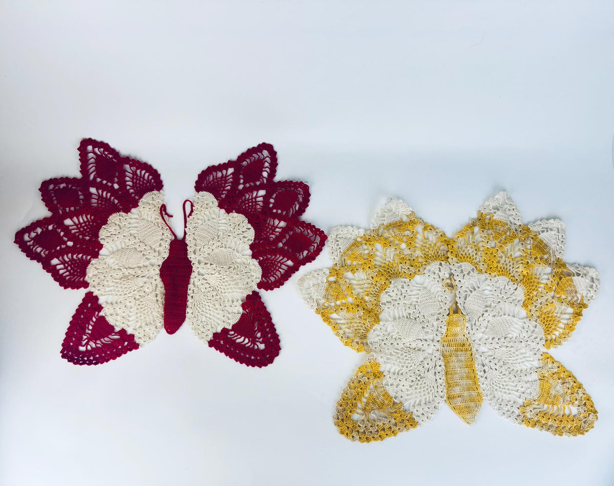 Crimson butterfly doily beside yellow butterfly doily, viewed from above