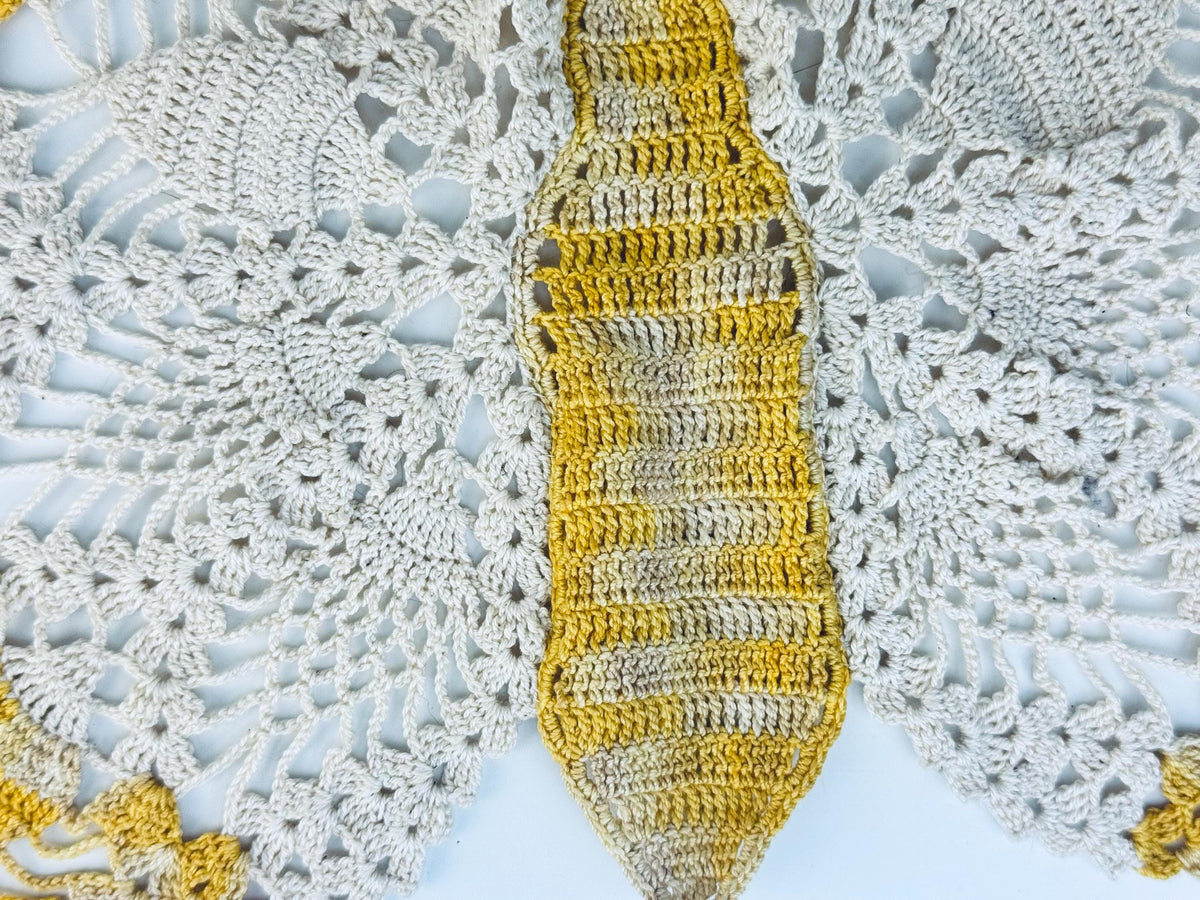 Close-up of yellow butterfly doily from top angle, showing body and lace wings