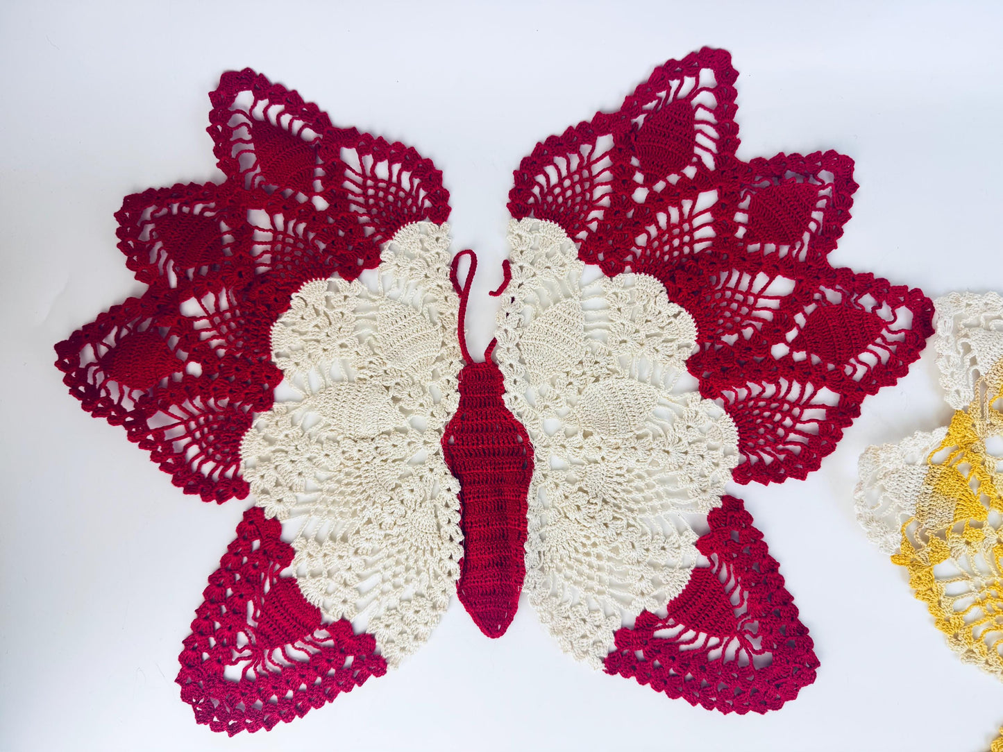 Close-up of crimson butterfly doily showing antennae and fine lace details