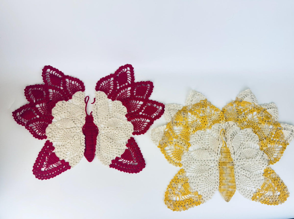 Pair of crocheted butterfly doilies in crimson and yellow, displayed side by side