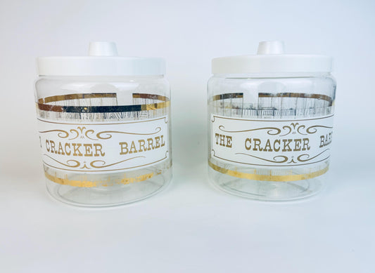 Pair of vintage Pyrex Cracker Barrel glass jars with white lids and gold decal design.