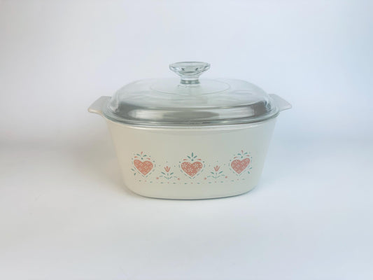 Vintage CorningWare Forever Yours casserole dish with pink heart pattern and clear glass lid. 