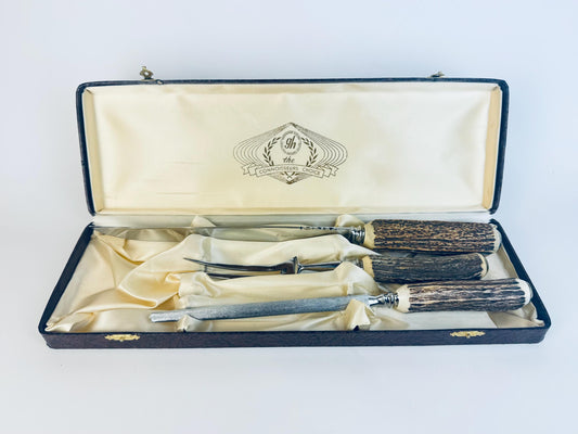 Vintage 1960s Glo-Hill “Connoisseurs Choice” three-piece carving set made in Sheffield, England, featuring polished stainless steel blades and genuine stag-horn antler handles, displayed in its original cream satin-lined presentation case marked with the Glo-Hill logo.