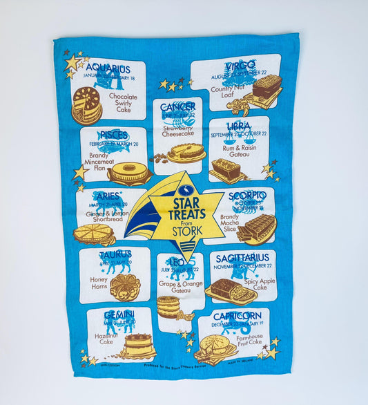 Tea towel with astrological signs and corresponding treats on a blue background