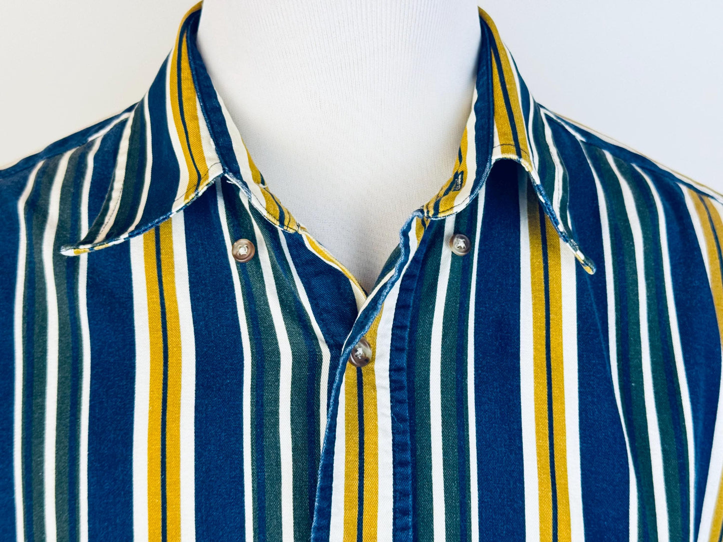 Striped shirt with blue, yellow, and white pattern on a mannequin against a white background