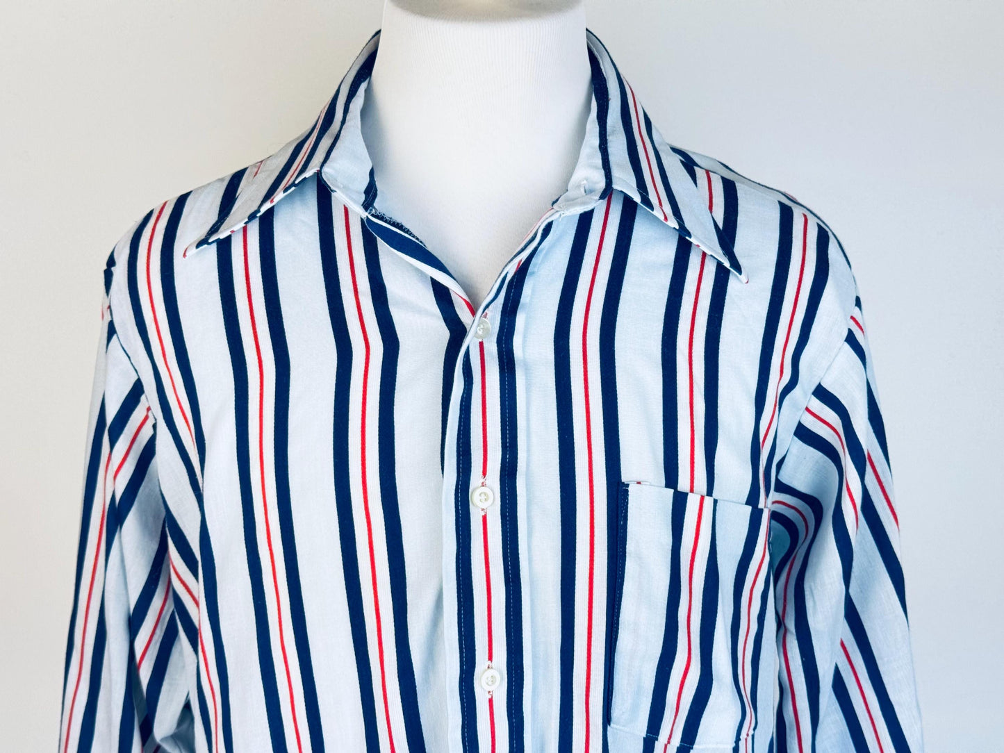 Blue red and white striped shirt on a mannequin against a plain background