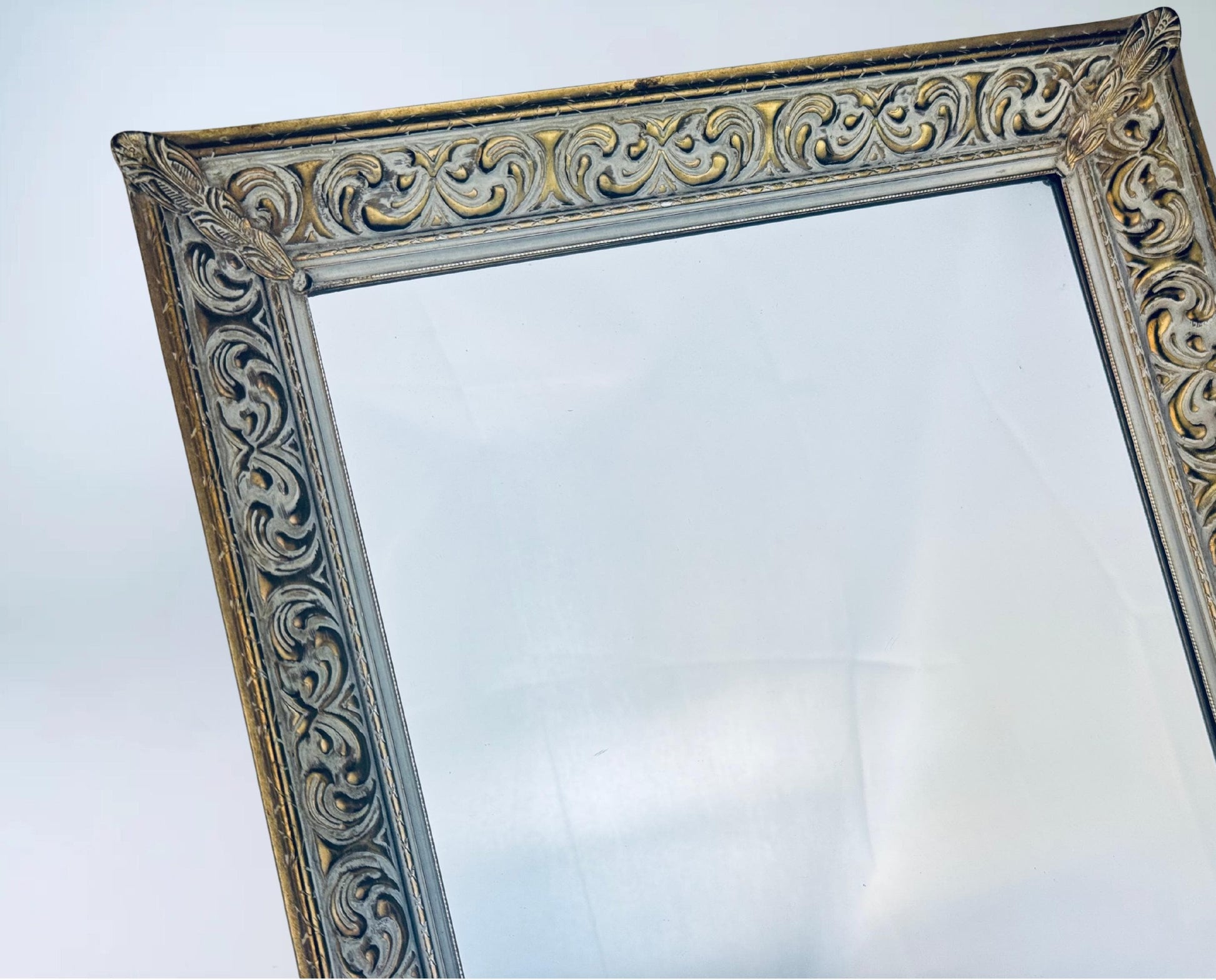 Decorative mirror with ornate gold and silver frame on a white background