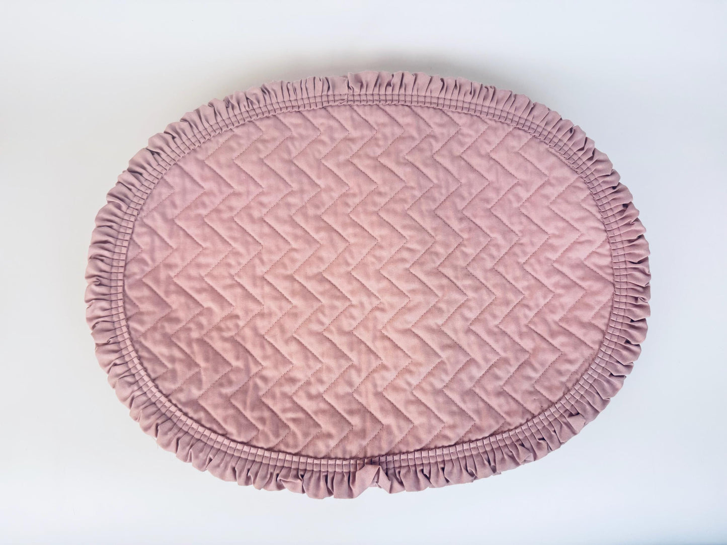 Pink textured round placemats with ruffled edges on a white background