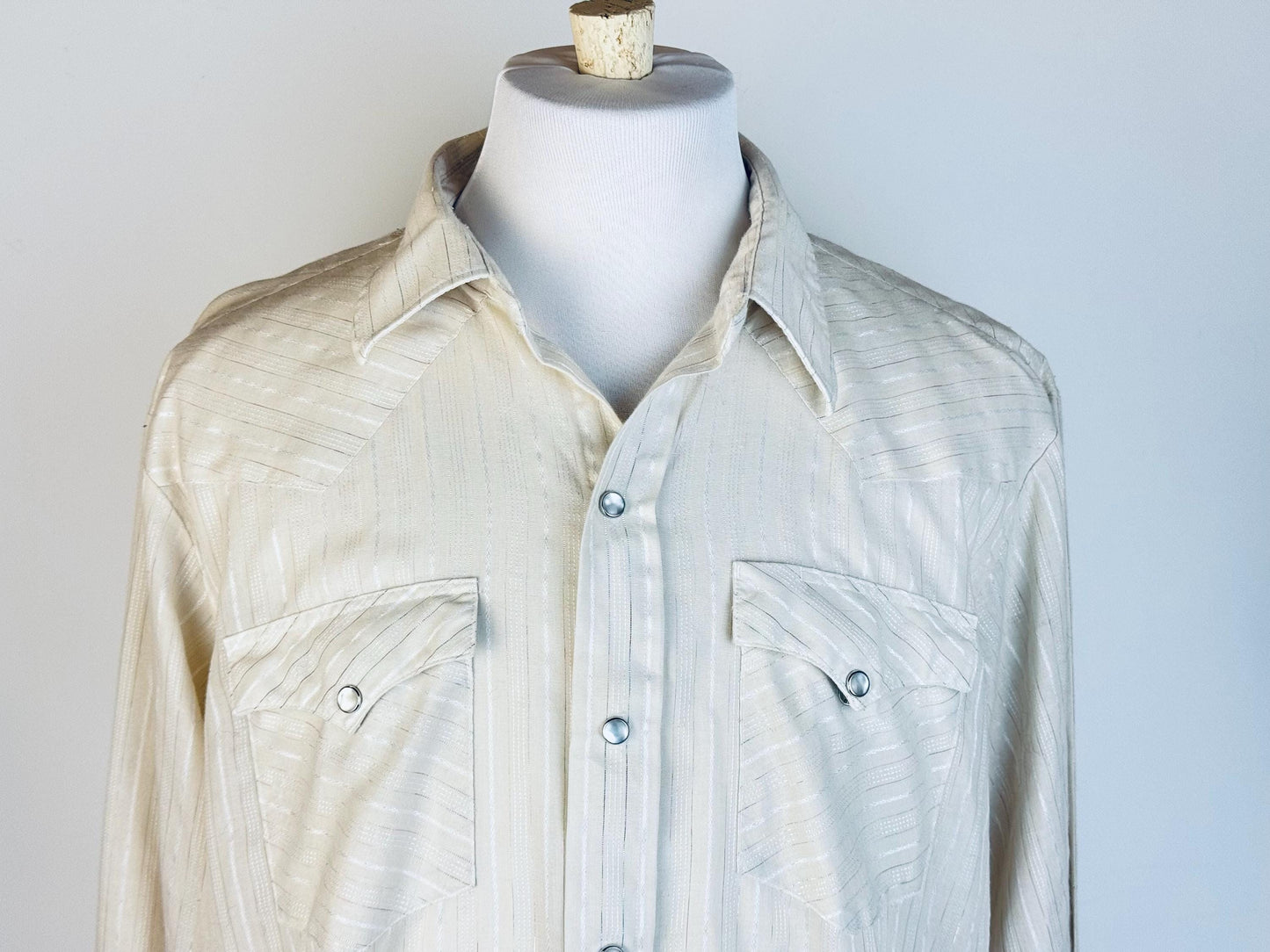 Light-colored shirt on a mannequin against a plain background