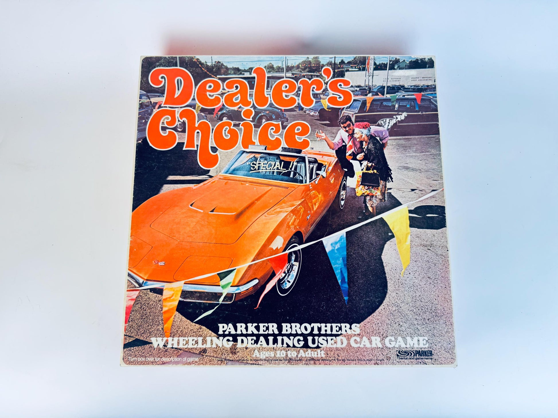Game box for 'Dealer's Choice' by Parker Brothers featuring an orange car and people around it.