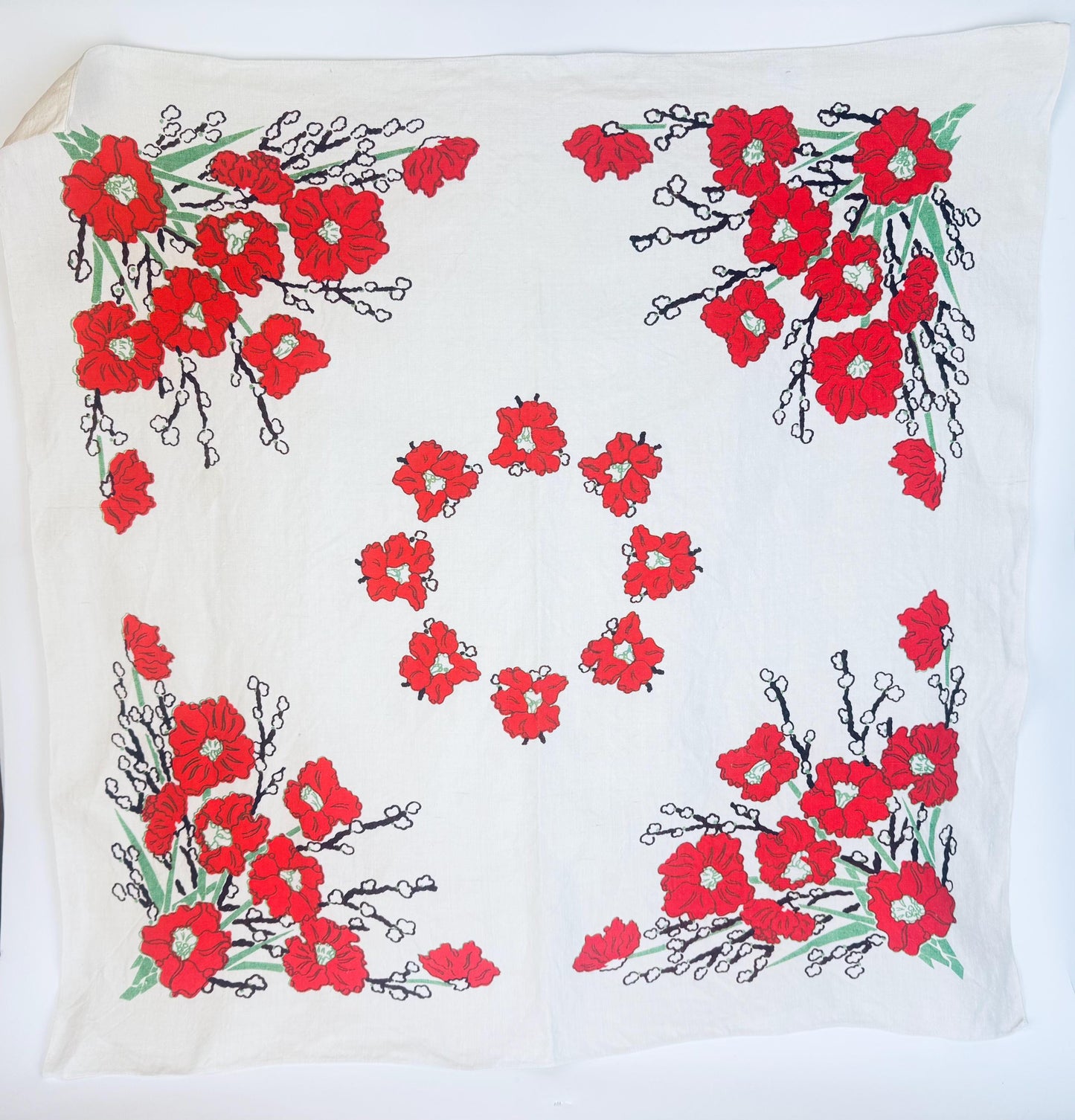 Vintage 1950s square linen tablecloth with bold red poppy floral print in each corner and a circular wreath design in the center, displayed flat on a white background.