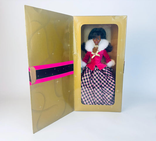 Barbie doll in a gold box with a pink and black ribbon on a white background