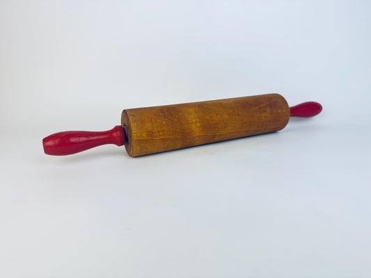 Wooden rolling pin with red handles on a white background