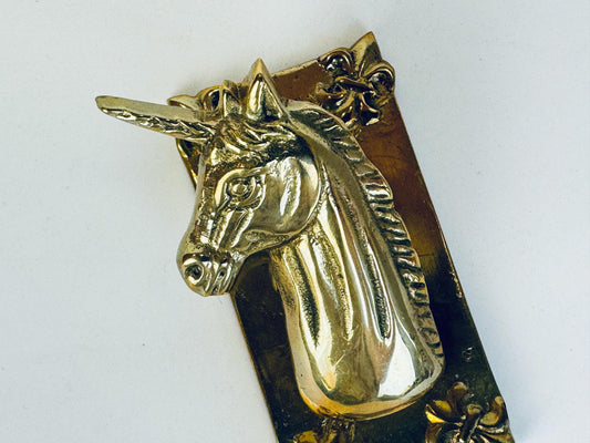 Vintage brass unicorn paper or memo clip featuring a detailed unicorn head with a flowing mane and fleur-de-lis accents on a rectangular brass base, shown against a white background.