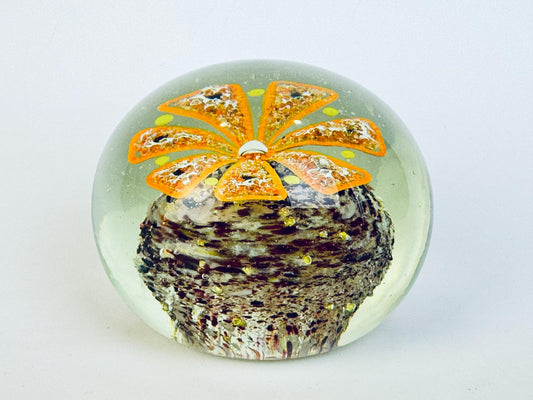 Decorative paperweight with an orange flower design on a white background